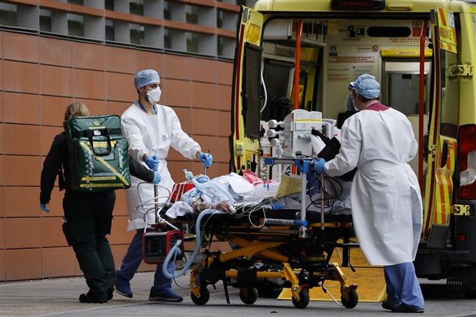 Nhân viên y tế chuyển bệnh nhân nhiễm COVID-19 tới bệnh viện ở London, Anh. Ảnh: AFP/TTXVN