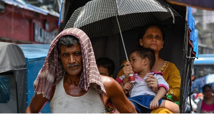 Một người mẹ che ô cho con để tránh nắng nóng ở Kolkata, Ấn Độ, ngày 3/7/2023. (Ảnh: Getty Images)