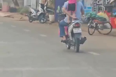 Bé gái đứng chênh vênh trên yên xe máy