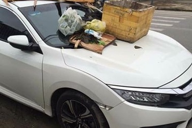 Ô tô đậu trước lối vào nhà dân bị đổ rác đầy nắp ca pô