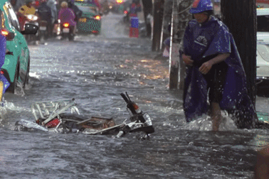 Người dân TPHCM té ngã trên đường ngập do mưa lớn