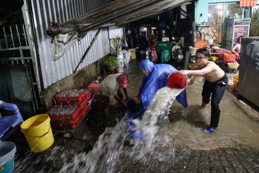 Người dân TPHCM dùng xô tát nước ra khỏi nhà sau cơn mưa lớn