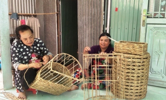 Phụ nữ xã Mỹ Bình (thị xã Ngã Năm) nhận nguyên liệu lục bình đan giỏ về nhà làm, giúp có thêm thu nhập.