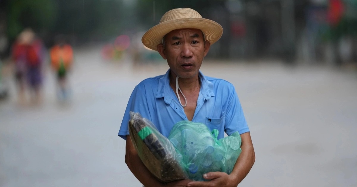 Trẻ nhỏ cùng người lớn vượt qua nước lụt để nhận hàng tiếp tế (Ảnh: Hữu Khoa).