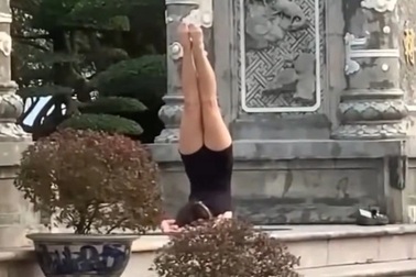 Một phụ nữ tập yoga trước cổng chùa