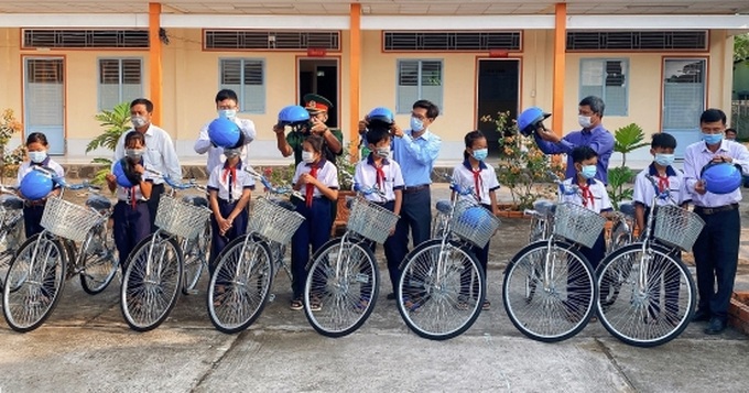 Ông Tiêu Minh Dưỡng (người thứ hai bên trái sang, hàng sau), Phó Giám đốc Sở LĐ-TB&XH TP. Cần Thơ cùng lãnh đạo địa phương trao xe đạp cho các em học sinh.