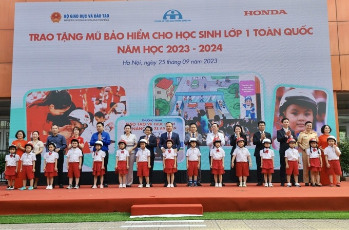 Ông Khuất Việt Hùng, Phó Chủ tịch chuyên trách Ủy ban ATGT Quốc gia và đại diện các đơn vị trao tặng mũ bảo hiểm cho học sinh lớp 1 Trường Tiểu học Phú Đô.