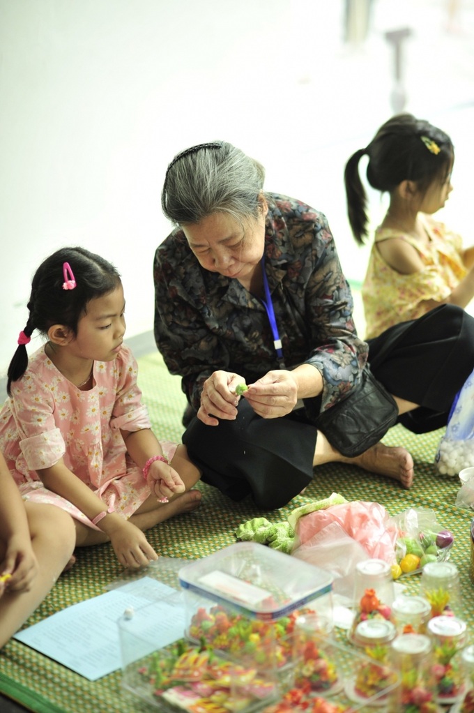 Nghệ nhân Nguyệt Ánh hướng dẫn trẻ em làm hoa quả bằng bột.