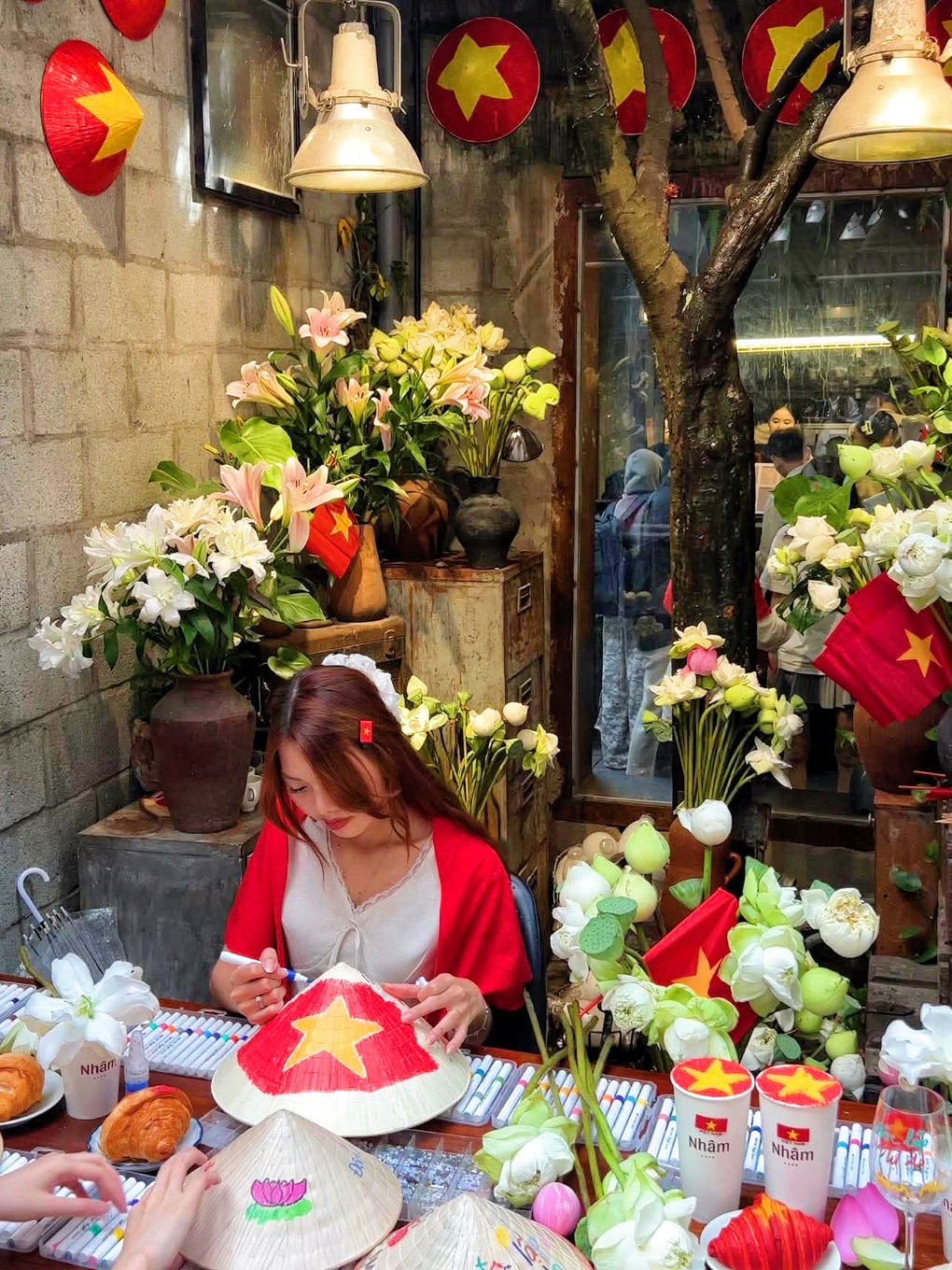 Das Café in Ho-Chi-Minh-Stadt ist farbenfroh mit Flaggen und Blumen und nutzt die Malerei konischer Hüte, um vom 2. bis 1. September Kunden anzulocken. Quán cà phê ở TPHCM rực rỡ cờ hoa, tung chiêu vẽ nón lá hút khách dịp 2/9 - 1