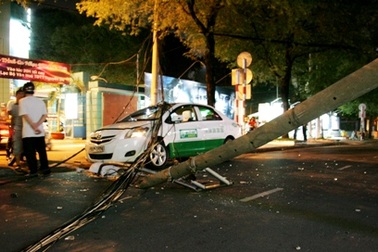 Trụ điện gãy kéo đổ cột đèn, đè vào taxi