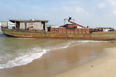 Một tàu sắt vô chủ bị sóng đánh dạt vào bờ biển