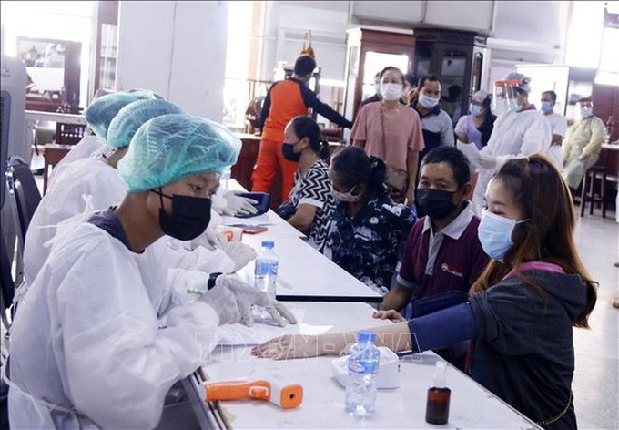Các nhân viên y tế tại một điểm tiêm ở thủ đô Vientiane (Lào) kiểm tra sức khỏe cho người dân trước khi tiêm vaccine. Ảnh: Phạm Kiên/PV TTXVN tại Lào