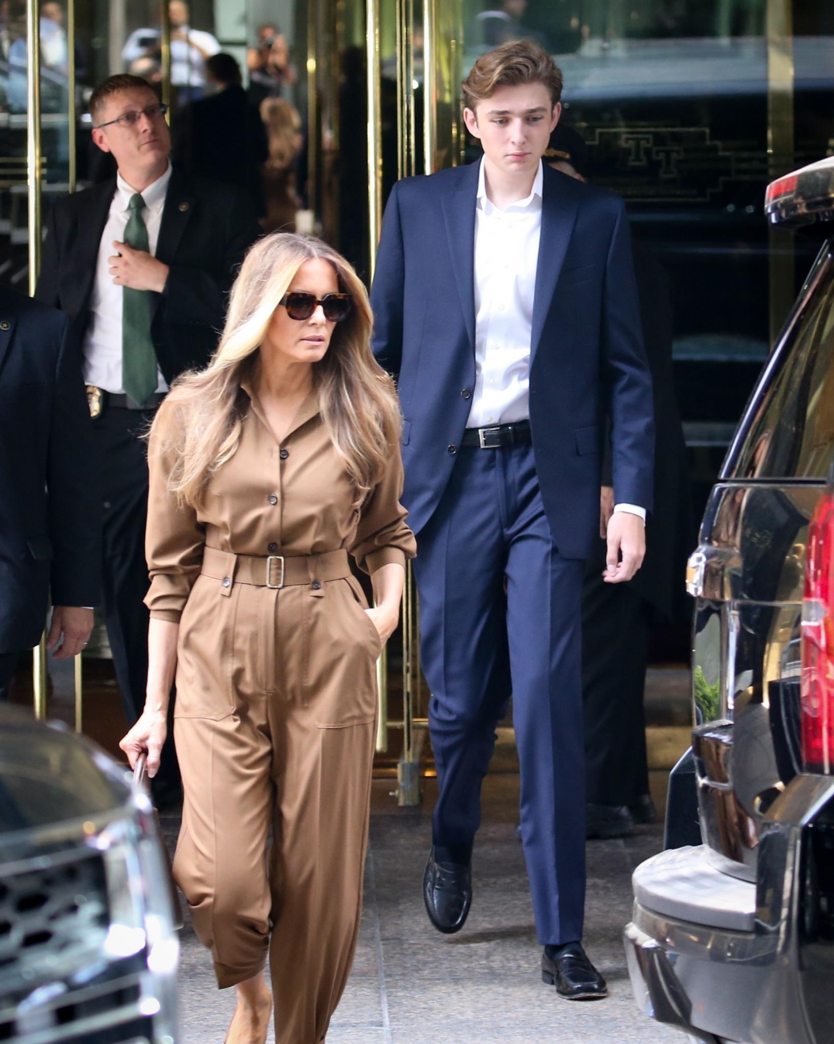 Barron Trump diện suit xanh dương với sơ mi trắng khi cùng mẹ rời khỏi Tháp Trump ở khu dân cư Midtown, New York (Mỹ) (Ảnh: Daily Mail).