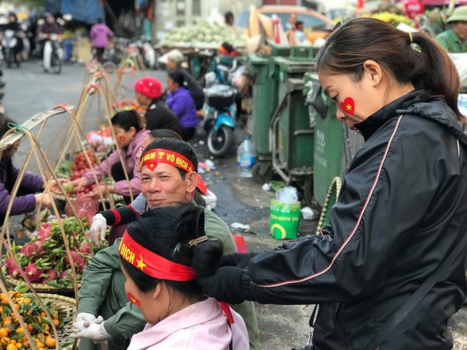 Hàng rong chợ Đồng Xuân vừa bán hàng vừa tranh thủ lên đồ cổ vũ U22 Việt Nam - Ảnh 1.