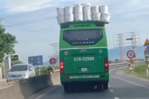 Xe khách chất hàng cồng kềnh trên nóc, chạy băng băng trên đường