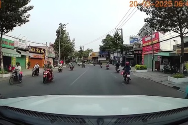 Người đàn ông đi xe máy đẩy bé đi xe đạp phóng băng băng trên đường