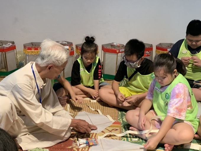 Nghệ nhân Nguyễn Văn Quyền hướng dẫn các em nhỏ làm diều rô tại Bảo tàng Dân tộc học Việt Nam.