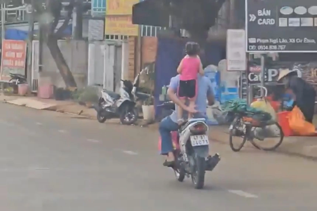 Người đàn ông cho bé gái làm xiếc trên yên xe máy - 1 Người đàn ông cho bé gái làm xiếc trên yên xe máy - 1