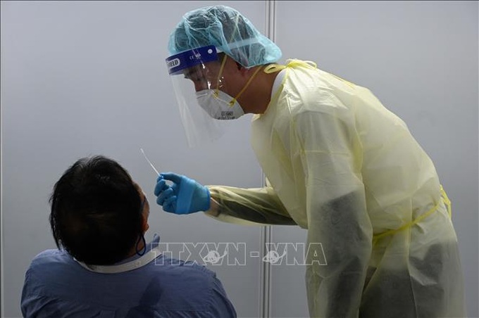 Nhân viên y tế lấy mẫu xét nghiệm COVID-19 cho người dân tại Singapore. Ảnh: AFP/TTXVN