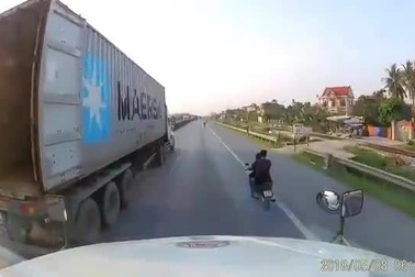 Hai nam thanh niên đầu trần chạy xe máy thách thức trước mũi xe container