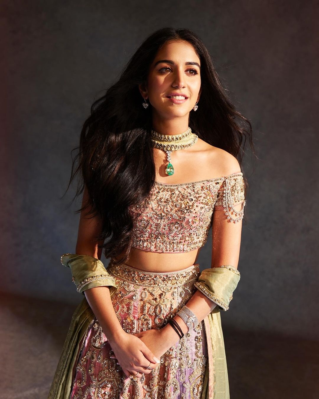 Radhika Merchant bắt đầu chuỗi ngày cưới bằng chiếc lehenga (y phục của phụ nữ Ấn Độ) màu pastel của nhà thiết kế Abu Jani Sandeep Khosla, lấy cảm hứng từ đèn chùm. Cô diện trang phục này trong buổi lễ sangeet (lễ truyền thống trước đám cưới). Thiết kế được thêu thủ công bằng pha lê Swarovski, kết hợp với chiếc áo cánh pha lê trễ vai (Ảnh: @signe_vilstrup).