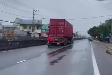 Người đi xe máy liều lĩnh bám đuôi container để tránh gió