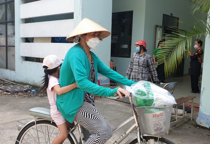 Chị Mỹ Hạnh tất tả đạp xe chở con đi nhận từ sớm.