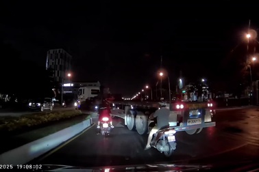 Người đi xe máy chen vào khoảng trống của xe đầu kéo đang chuyển hướng