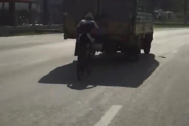 Người đàn ông đi xe đạp bám sát đuôi xe tải để... tránh nắng