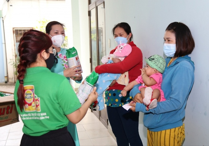Người dân có hoàn cảnh khó khăn vui mừng bế con đi nhận sữa tại phường 7, quận 8, TP.HCM.