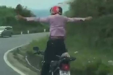 Nam thanh niên buông tay lái, đứng thẳng người, lao xe vun vút trên đường