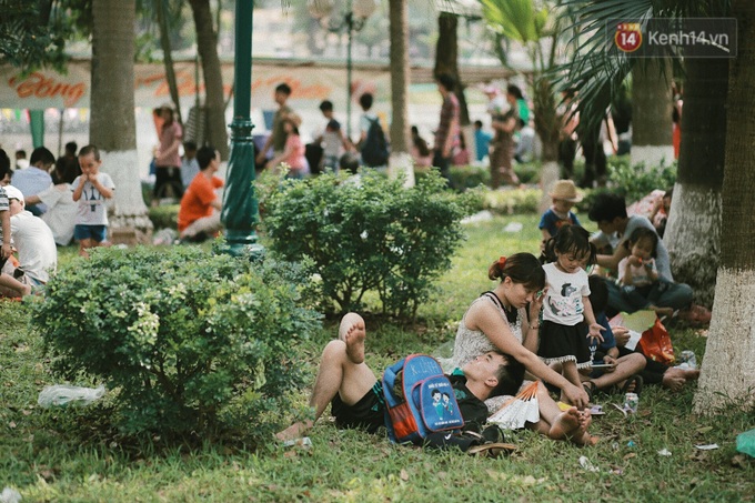 Nhiều gia đình nằm nghỉ ngơi dưới bóng cây trong công viên lúc trưa nắng.