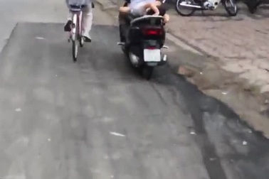 Mẹ đầu trần đèo con nằm ngửa trên xe máy