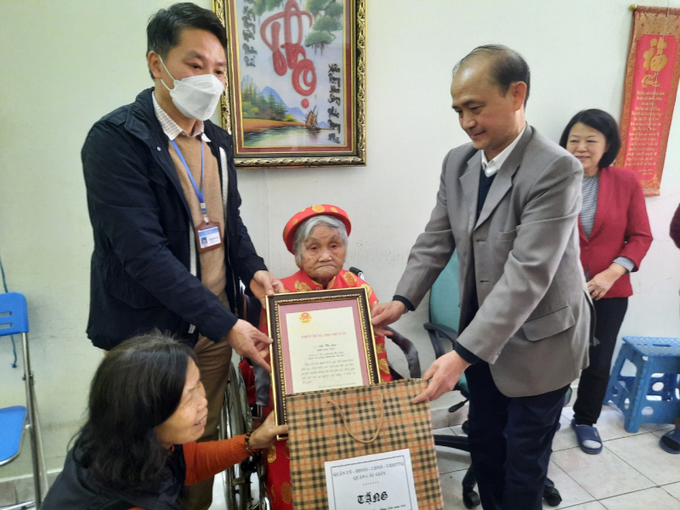 Ông Phạm Văn Triển, Ủy viên thường vụ, Trưởng ban Tổ chức Quận ủy quận Cầu Giấy và ông Phạm Văn Lợi, Chủ tịch UBND phường Mai Dịch thăm tặng quà và trao thiếp mừng thọ của Chủ tịch nước tới cụ Vũ Thị San - tròn 100 tuổi, phường Mai Dịch.