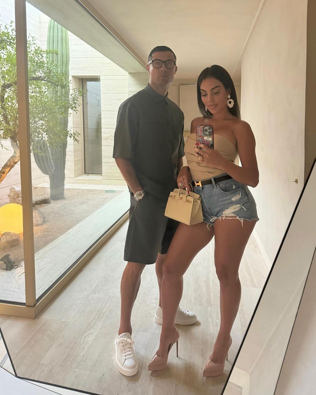 Georgina Rodriguez ưa chuộng những gam màu trung tính như đen, trắng và nude. Georgina mặc quần short denim khoe chân dài kết hợp cùng áo cúp ngực màu nude để lộ thân hình quyến rũ. Cô hoàn thiện vẻ ngoài của mình bằng một chiếc túi Hermes Kelly và thắt lưng đặc trưng của Hermes. Người đẹp cũng không quên sử dụng phụ kiện bông tai to bản và những chiếc nhẫn kim cương lớn cùng vòng tay Cartier (Ảnh: Daily Mail).