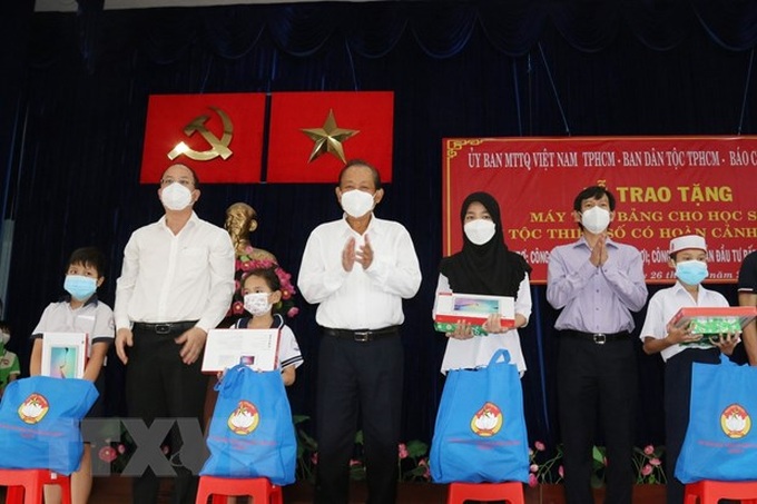 Ông Trương Hòa Bình, nguyên Ủy viên Bộ Chính trị, nguyên Phó Thủ tướng Thường trực Chính phủ, và ông Nguyễn Hồ Hải, Phó Bí thư Thành ủy Thành phố Hồ Chí Minh (thứ 2 từ trái sang) trao tặng máy tính bảng cho các học sinh dân tộc Chăm và Khmer. (Ảnh: Xuân Khu/TTXVN)