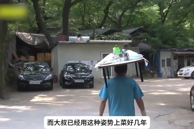 Chủ nhà hàng đội chiếc bàn nặng 40kg chất đầy thức ăn lên đầu phục vụ khách