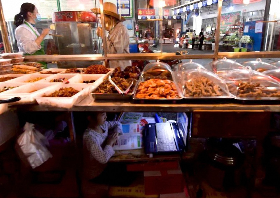 Trung Quốc: Bé gái ngồi học bên dưới xe bán hàng của mẹ gây sốt mạng xã hội - 1 Trung Quốc: Bé gái ngồi học bên dưới xe bán hàng của mẹ gây sốt mạng xã hội - 1