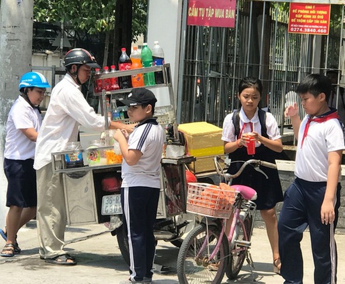 Hiểm họa từ hàng quà rong trước cổng trường học - Ảnh 1. Hiểm họa từ hàng quà rong trước cổng trường học - Ảnh 1.
