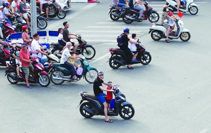 Trẻ em ngồi sau xe máy nhưng không có mũ bảo hiểm là điều khá phổ biến trên đường phố.