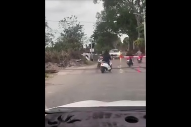 Người đi xe máy đua nhau vượt đường sắt dù chắn tàu đã hạ
