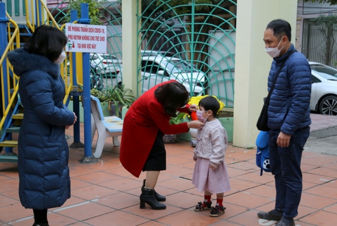 Giáo viên Trường Mầm non Hoa Lan (phường Hồng Hải, TP Hạ Long) đón các em học sinh từ cổng trường, ân cần hướng dẫn các em học sinh đeo khẩu trang đúng quy cách. Ảnh baoquangninh.com.vn