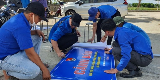 Các đoàn viên thanh niên chuẩn bị lắp đặt biển cảnh báo phòng, chống đuối nước cho trẻ em tại xã Hải Phong, huyện Hải Lăng. Ảnh baoquangtri.vn