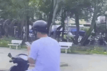 Nam thanh niên lái xe máy buông 2 tay, vừa bấm điện thoại vừa xỉa răng