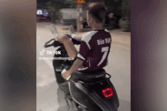 Nam thanh niên nằm ngửa trên yên, dùng chân lái xe, tay bấm điện thoại