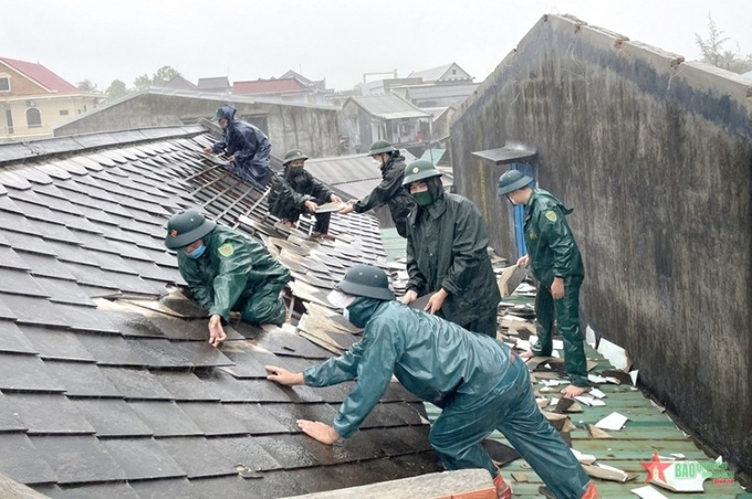 Lực lượng vũ trang tỉnh Thừa Thiên Huế giúp người dân xã Vinh Hiền lợp lại mái nhà bị lốc xoáy làm hư hại. Nguồn: QĐND