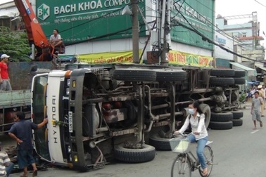 Xe tải chở thép cuộn lật nhào, người đi đường hoảng sợ