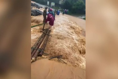 Giáo viên và người dân băng qua cầu tạm giữa dòng nước chảy xiết