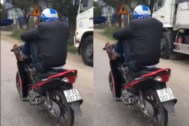 Nam thanh niên lái xe máy bằng chân, tay bấm điện thoại