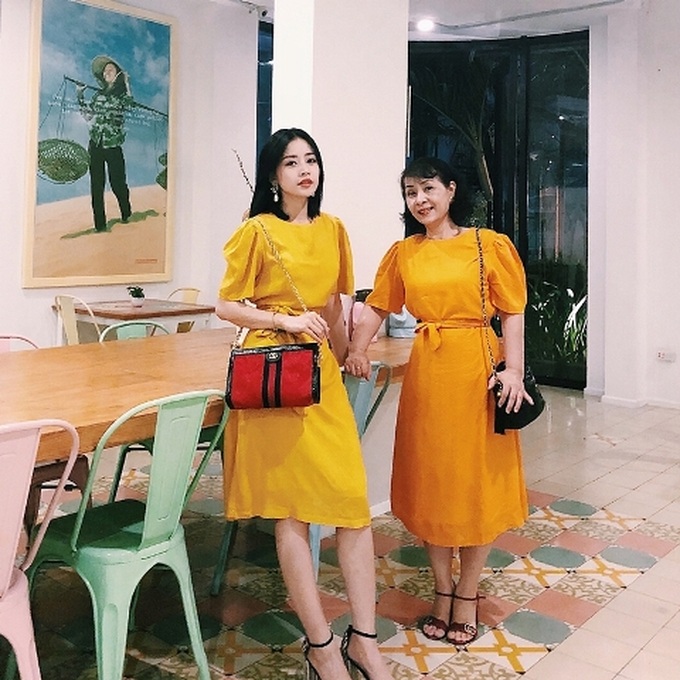 Chi Pu khiến fans thích thú khi chọn đầm đôi với mẹ. Thiết kế đầm đai quấn vàng rực giúp mẹ của người đẹp thêm trẻ trung trong khi Chi Pu cũng tô đậm được nét yêu kiều, duyên dáng.